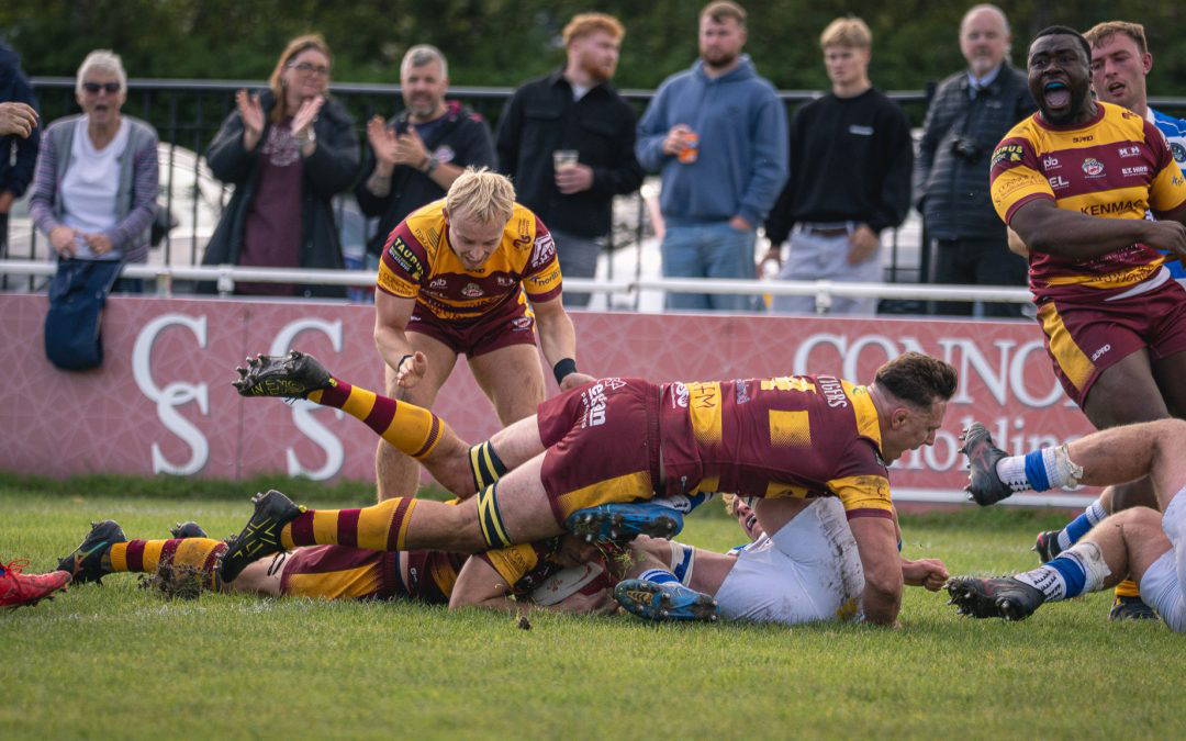 A Sedgley Park Tigers player grounds the ball for a try as teammates and the Park Lane crowd celebrate