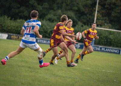 A Sedgley Park Tigers player passes along the backline as a Tynedale defender closes in