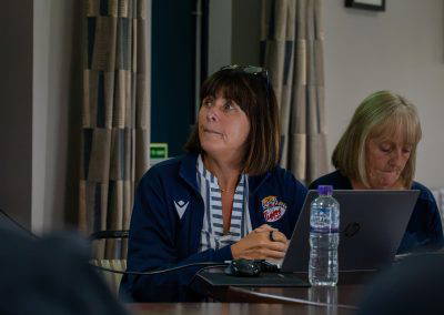 Two Sedgley Park volunteers in club jackets taking notes at the managers training evening