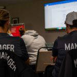 Two Sedgley Park team managers in club gilets watching the presentation at the managers training evening